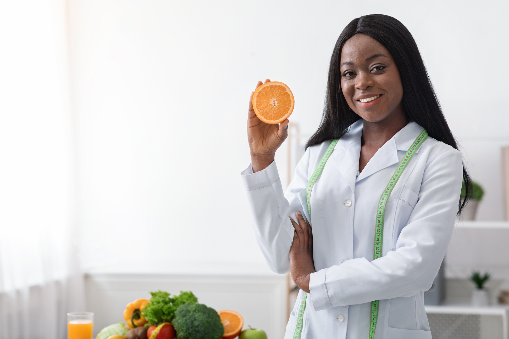 Positive black lady nutritionist holding orange half